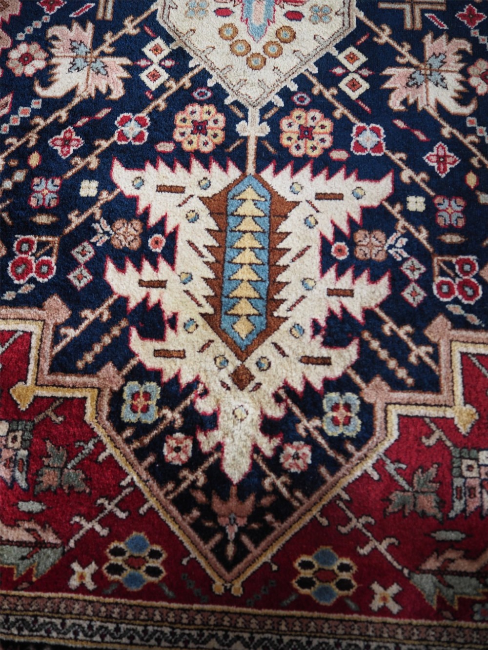 A large hand-knotted Persian wool carpet featuring a central cream medallion surrounded by navy blue and crimson sections filled with intricate floral motifs and framed by a detailed border. View IX