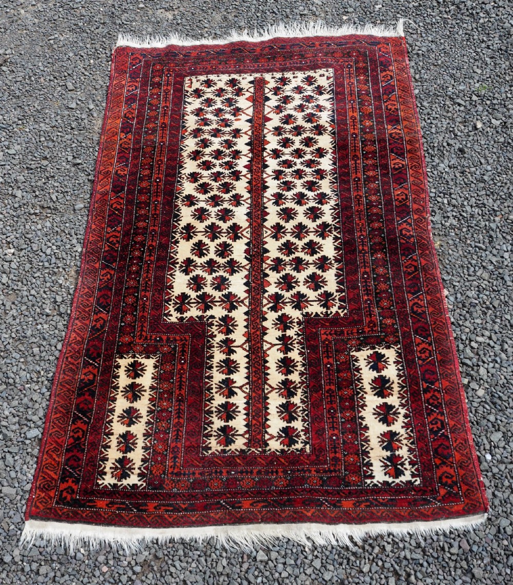 An antique hand-knotted Baluchi prayer rug featuring an off-white central field with geometric tree motifs framed by a deep red border. View II