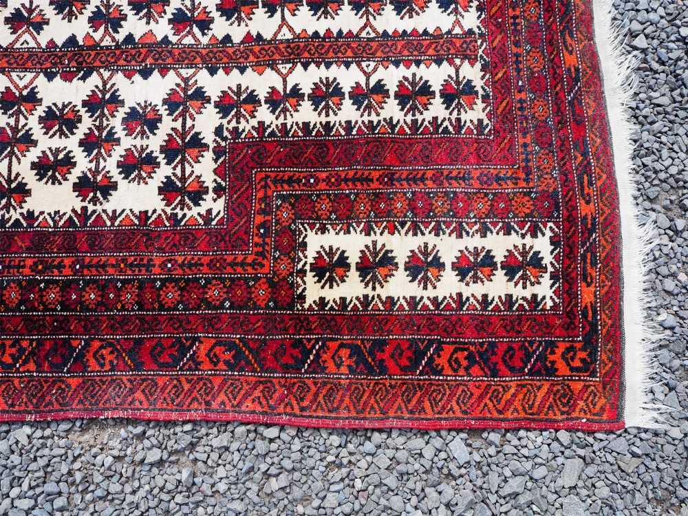 An antique hand-knotted Baluchi prayer rug featuring an off-white central field with geometric tree motifs framed by a deep red border. View IV