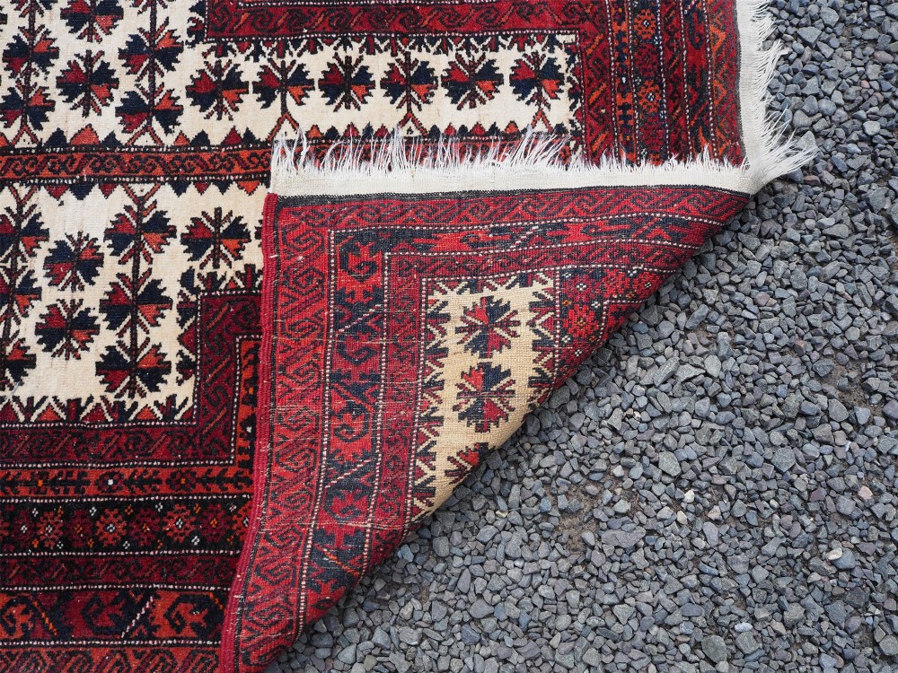 An antique hand-knotted Baluchi prayer rug featuring an off-white central field with geometric tree motifs framed by a deep red border. View VI