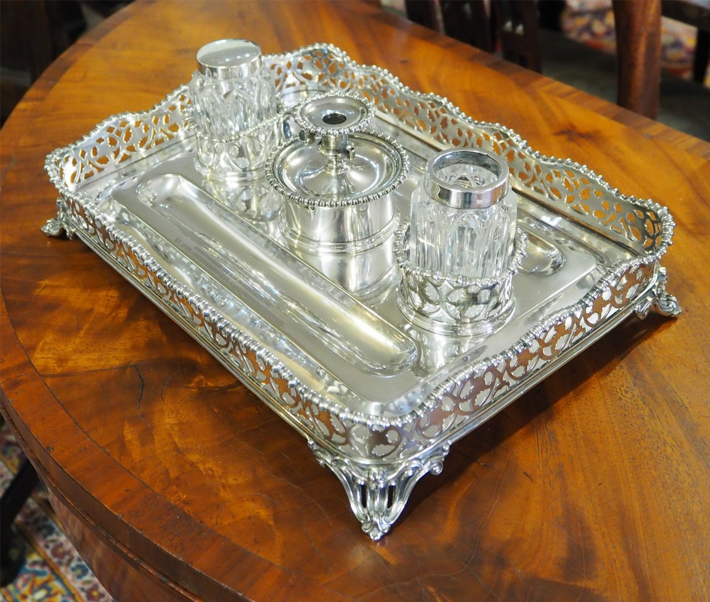 An antique silver-plated rectangular desk tray featuring a pierced gallery edge, two cut glass inkwells, a central taper holder, and a recessed pen groove. View III