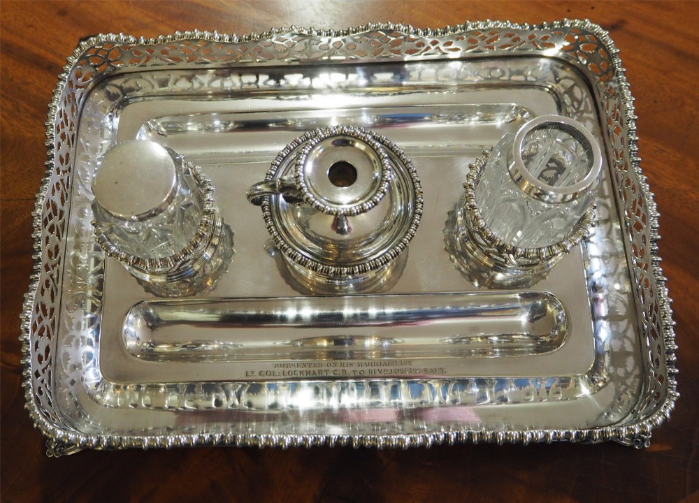 An antique silver-plated rectangular desk tray featuring a pierced gallery edge, two cut glass inkwells, a central taper holder, and a recessed pen groove. View IV