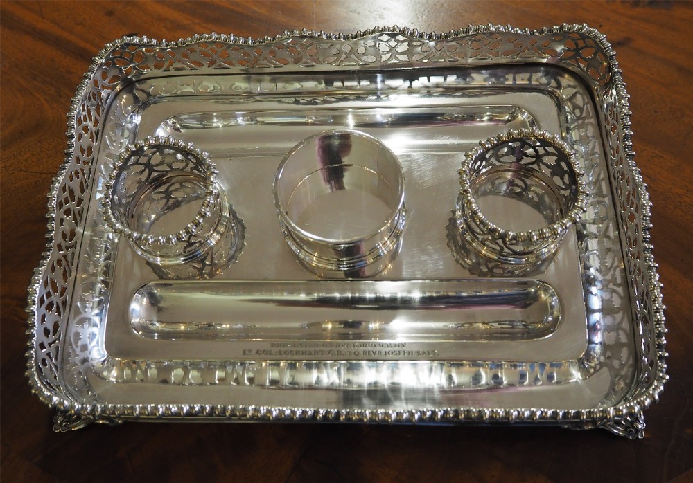 An antique silver-plated rectangular desk tray featuring a pierced gallery edge, two cut glass inkwells, a central taper holder, and a recessed pen groove. View VII