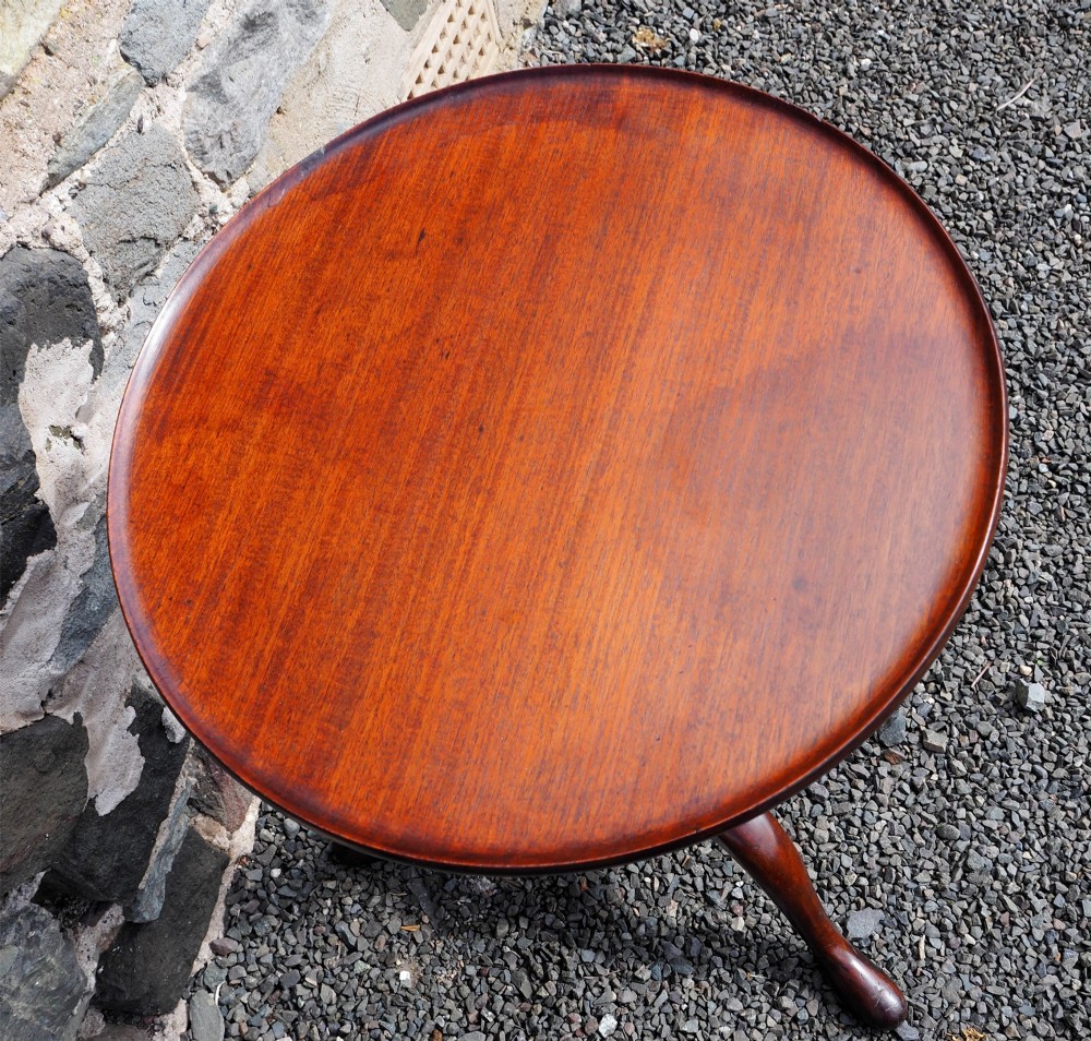 An early Georgian walnut candlestand featuring a circular dish-top surface set on a square adjustable pillar and a tripod base with cabriole legs. View V