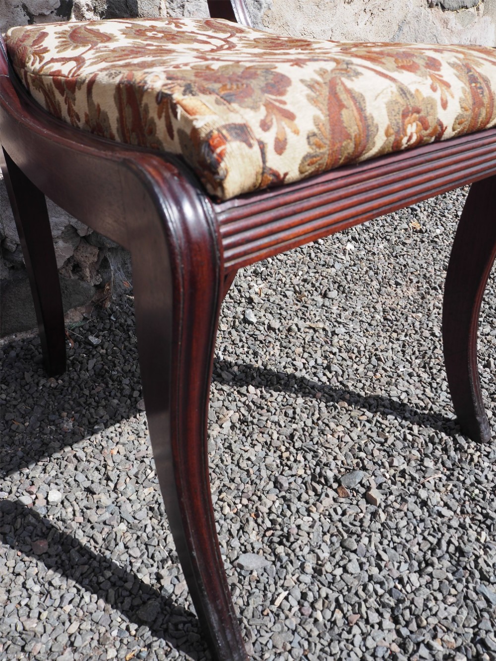 A Regency Cuban mahogany side chair featuring a carved crest rail, an anthemion splat, and a floral upholstered seat. View VI