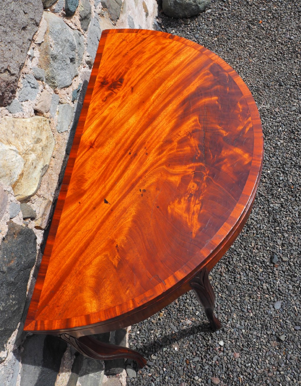 An 18th-century demilune folding card table crafted with flame mahogany veneer and carved slender legs. View IV