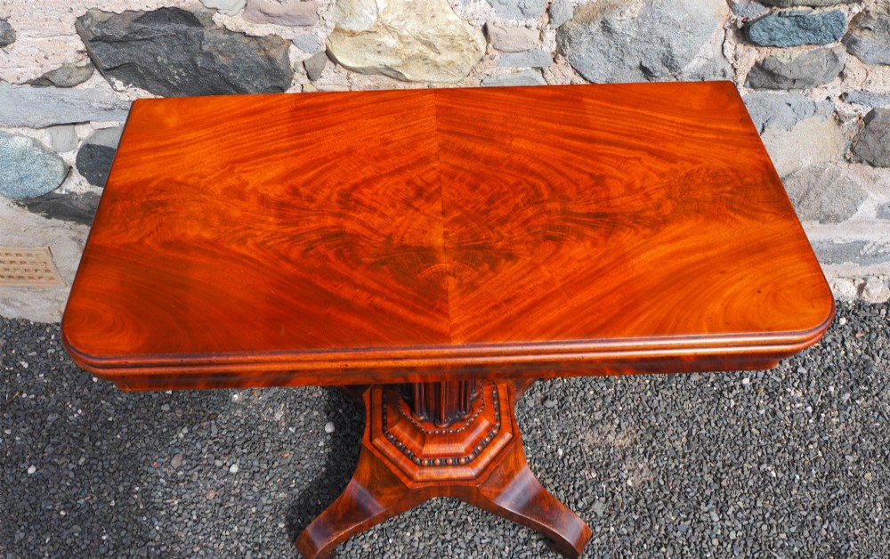 An 1830s William IV flame mahogany tea table featuring a fold-over rectangular top set on a fluted pedestal column with a four-point platform base and scroll feet. View III