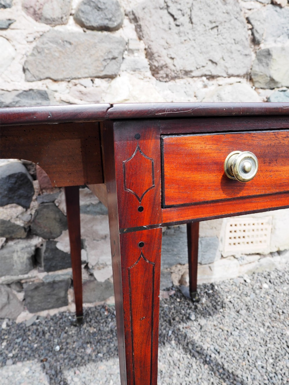 An 18th-century mahogany Pembroke table featuring two drop-leaf flaps, a single end drawer with brass knobs, and square tapered legs with subtle line inlay. View V