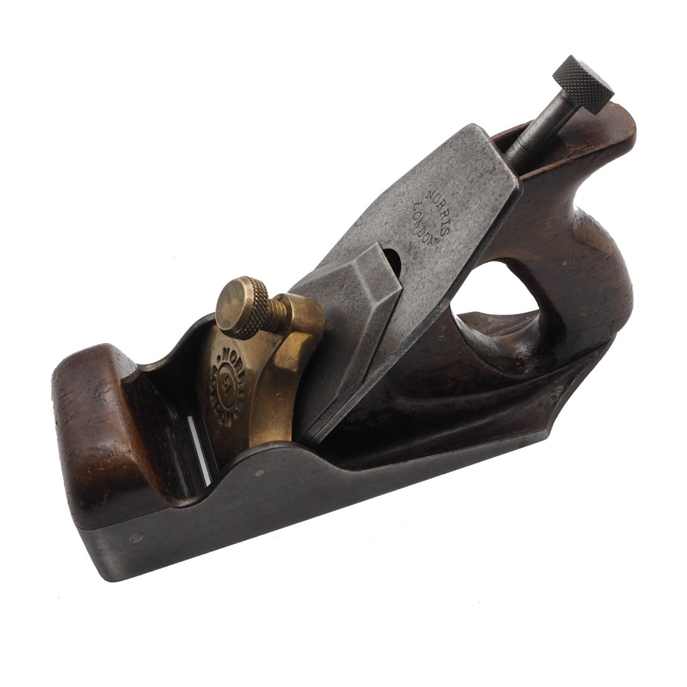 An antique Norris London A51 annealed iron smoothing plane featuring a dark hardwood infill, brass lever cap, and steel blade adjuster against a plain background. View II