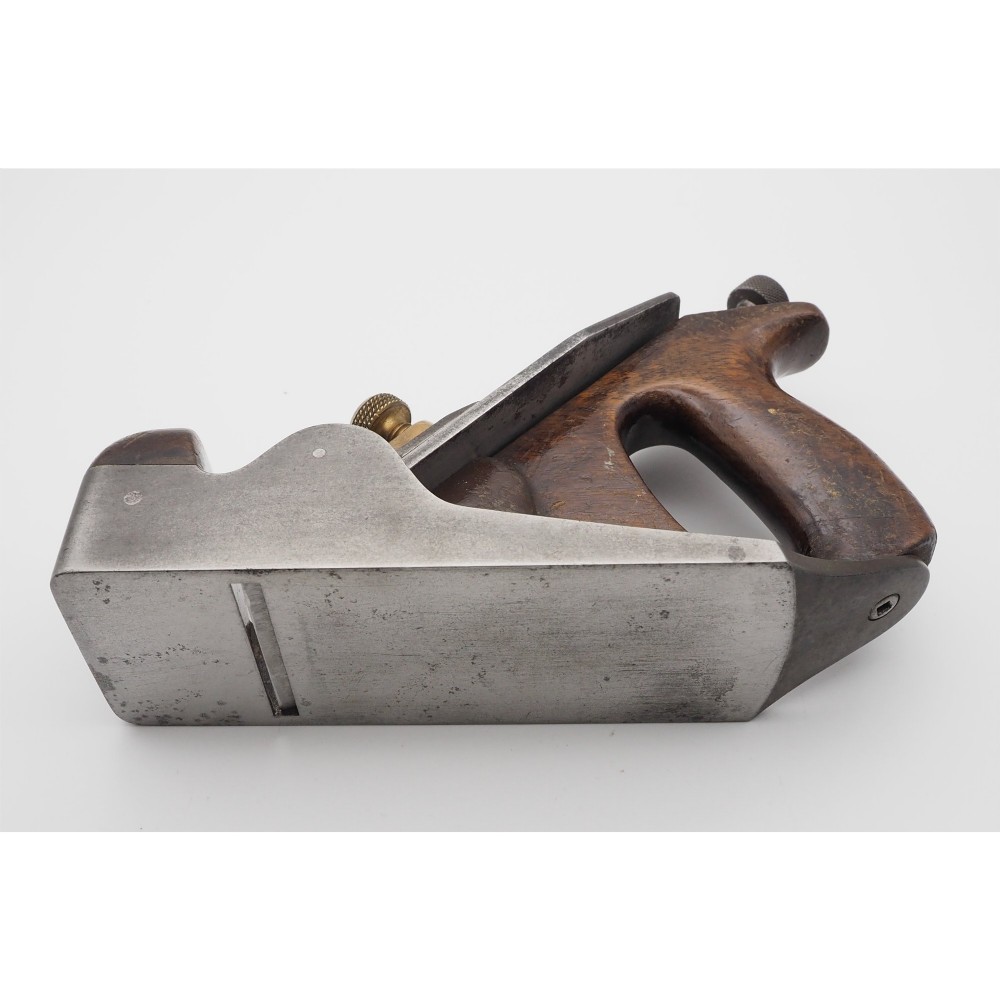 An antique Norris London A51 annealed iron smoothing plane featuring a dark hardwood infill, brass lever cap, and steel blade adjuster against a plain background. View IV
