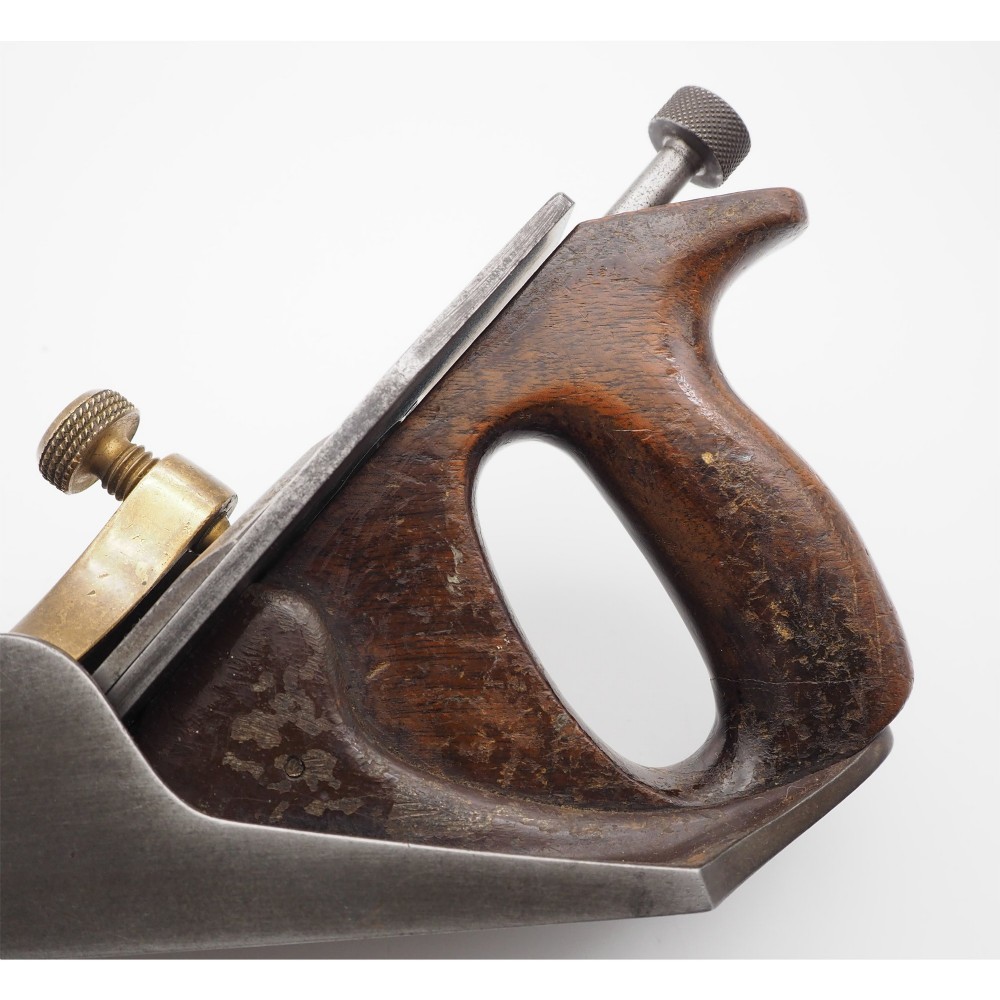 An antique Norris London A51 annealed iron smoothing plane featuring a dark hardwood infill, brass lever cap, and steel blade adjuster against a plain background. View V