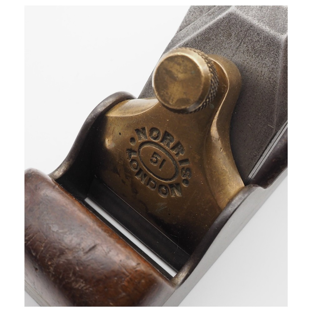 An antique Norris London A51 annealed iron smoothing plane featuring a dark hardwood infill, brass lever cap, and steel blade adjuster against a plain background. View VI