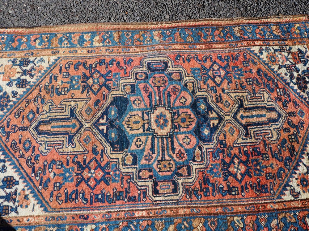 An antique Persian Hamadan hand-knotted wool rug featuring a central stepped medallion in blue, terracotta, and ivory tones with geometric borders. View V