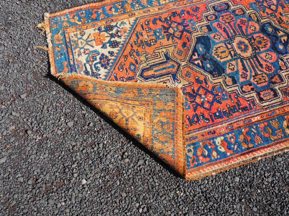 An antique Persian Hamadan hand-knotted wool rug featuring a central stepped medallion in blue, terracotta, and ivory tones with geometric borders. View VI