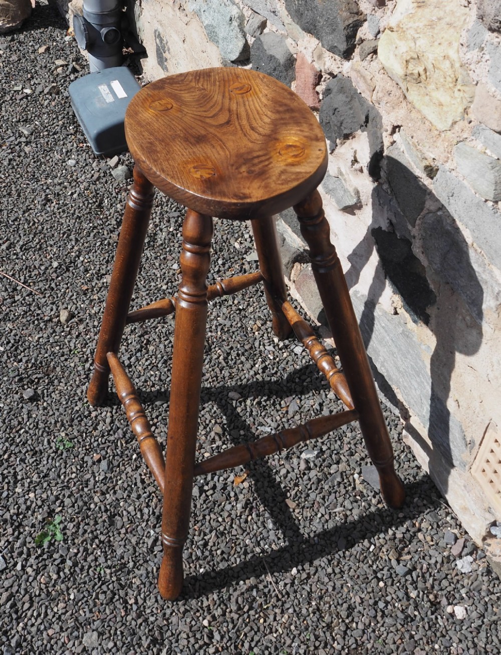 A 19th-century high stool constructed from ash and beech timber, featuring turned splayed legs, foot stretchers, and a rounded wooden seat. View II