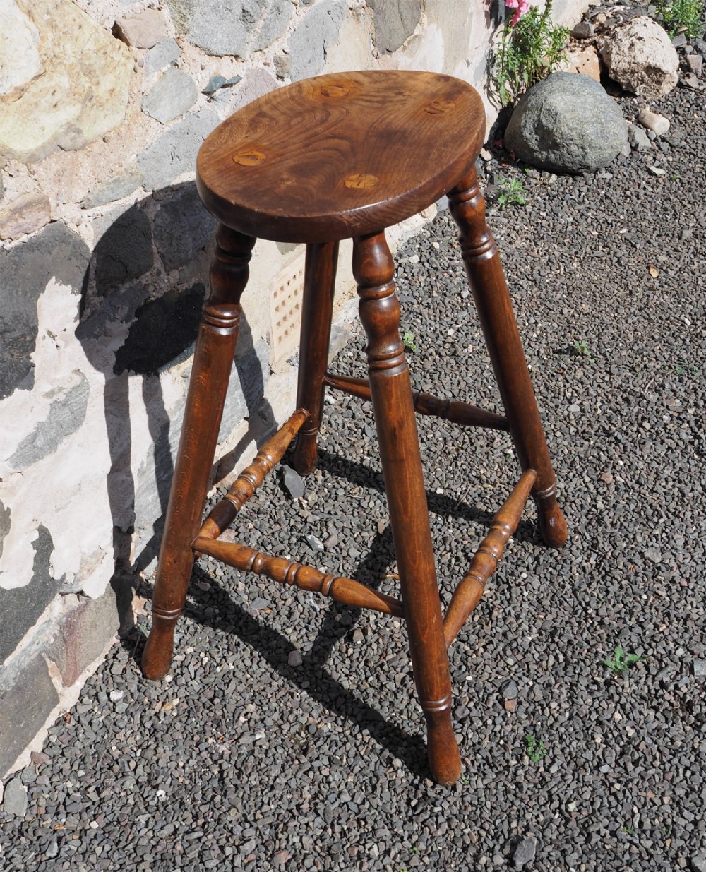 A 19th-century high stool constructed from ash and beech timber, featuring turned splayed legs, foot stretchers, and a rounded wooden seat. View III