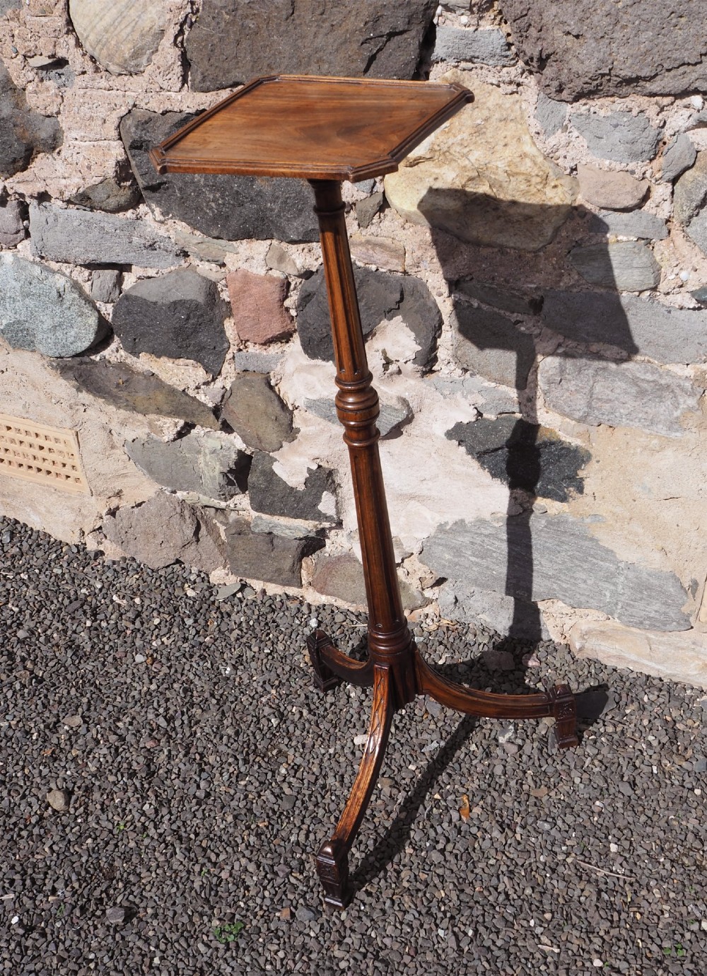 An 18th-century Dutch walnut torchere featuring a turned tapered column, shaped square tray top, and carved tripod legs.