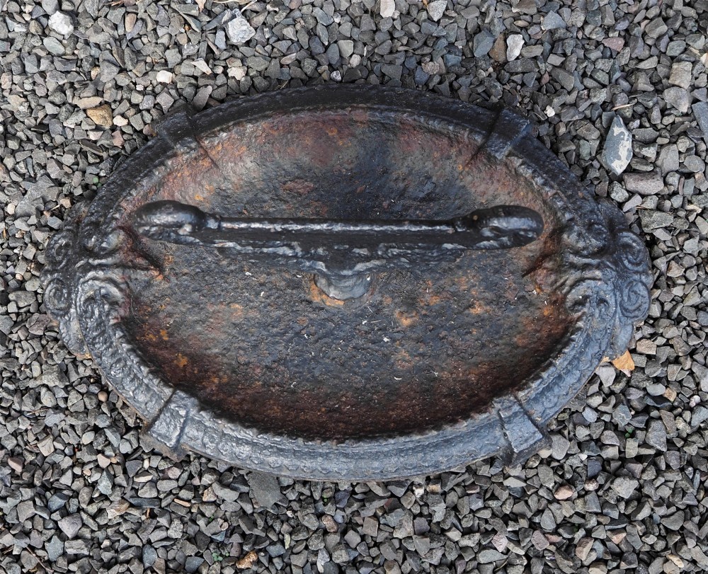 A Victorian cast iron boot scraper featuring a scrollwork top blade mounted above an oval tray with a textured border. View II