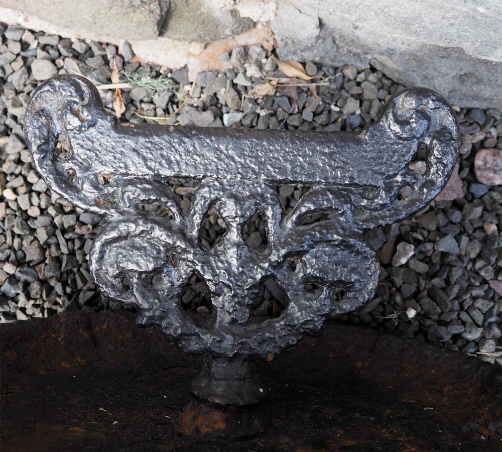 A Victorian cast iron boot scraper featuring a scrollwork top blade mounted above an oval tray with a textured border. View IV