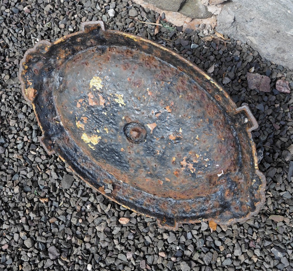 A Victorian cast iron boot scraper featuring a scrollwork top blade mounted above an oval tray with a textured border. View V