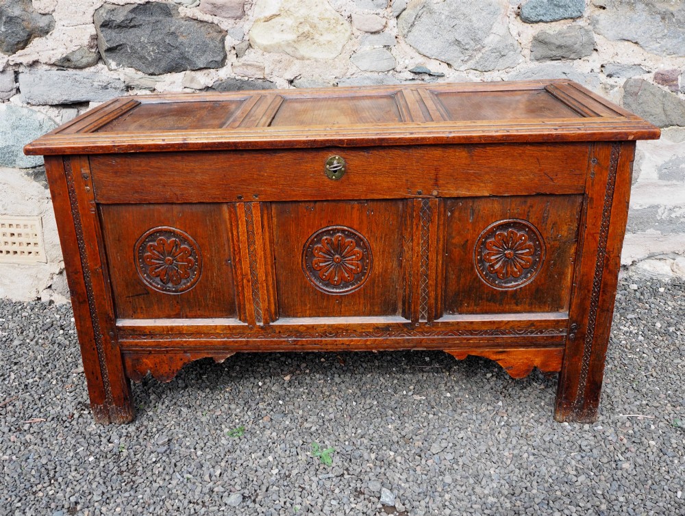 An early 18th-century oak coffer with a three-panel hinged top, carved rosette panels on the front, and a brass keyhole escutcheon. View II