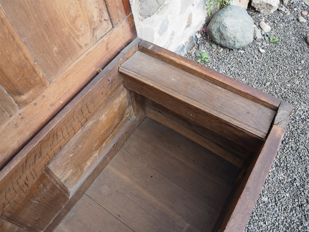 An early 18th-century oak coffer with a three-panel hinged top, carved rosette panels on the front, and a brass keyhole escutcheon. View VII
