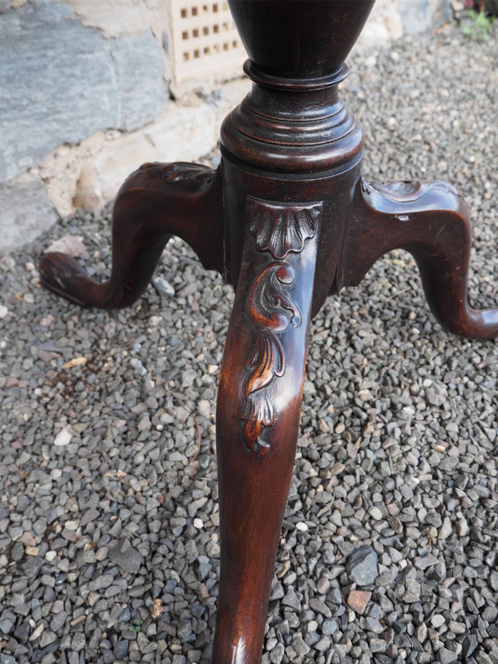 A Chippendale style dark mahogany tilt-top supper table featuring eight carved dished plate compartments around a central recess on a tripod cabriole base. View IV
