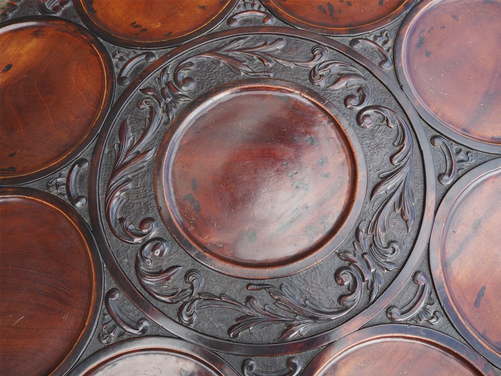 A Chippendale style dark mahogany tilt-top supper table featuring eight carved dished plate compartments around a central recess on a tripod cabriole base. View VIII