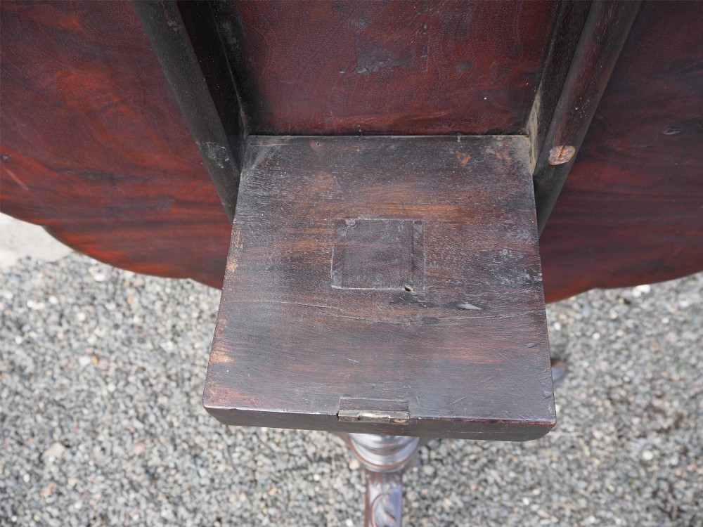 A Chippendale style dark mahogany tilt-top supper table featuring eight carved dished plate compartments around a central recess on a tripod cabriole base. View X