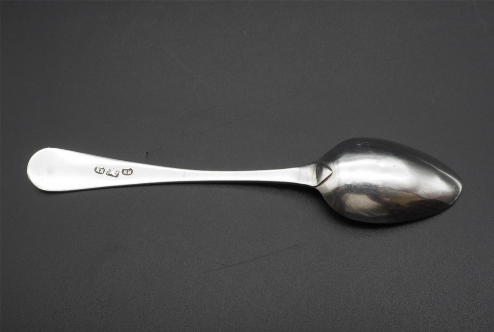 A set of four antique Scottish silver teaspoons with engraved terminal monograms displayed against a dark background. View IV
