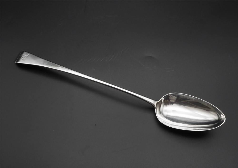 A Georgian sterling silver basting spoon featuring an elongated stem and deep oval bowl on a dark surface.