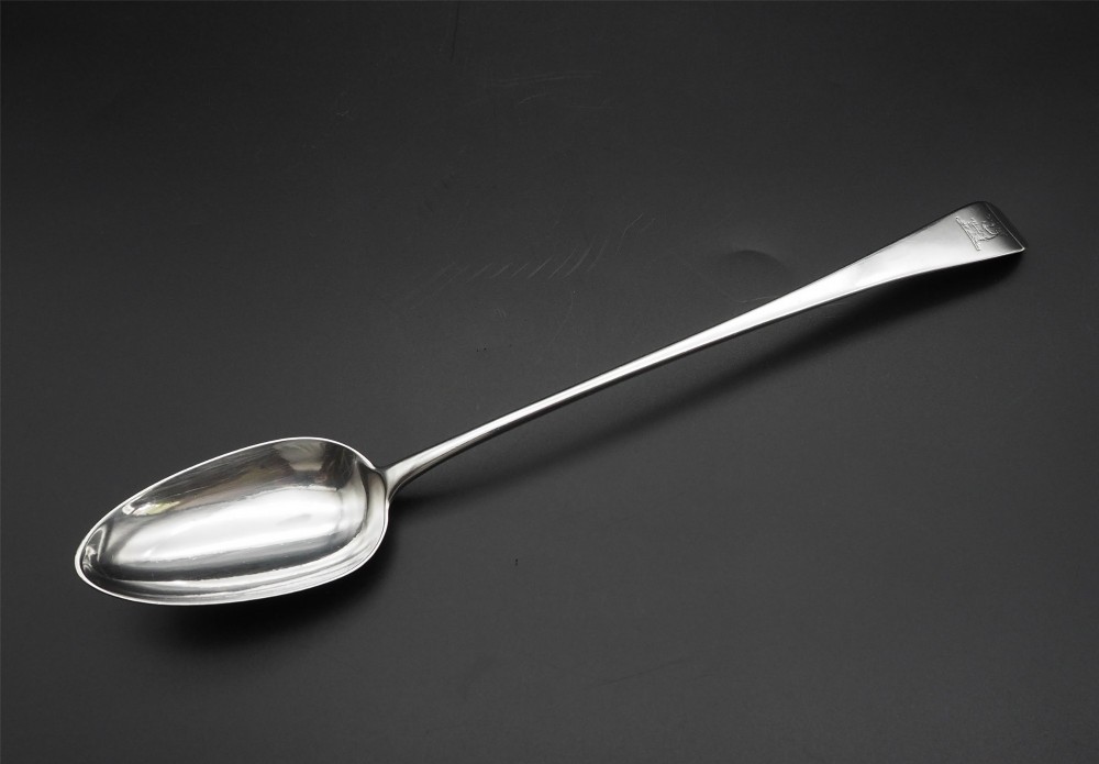 A Georgian sterling silver basting spoon featuring an elongated stem and deep oval bowl on a dark surface. View II