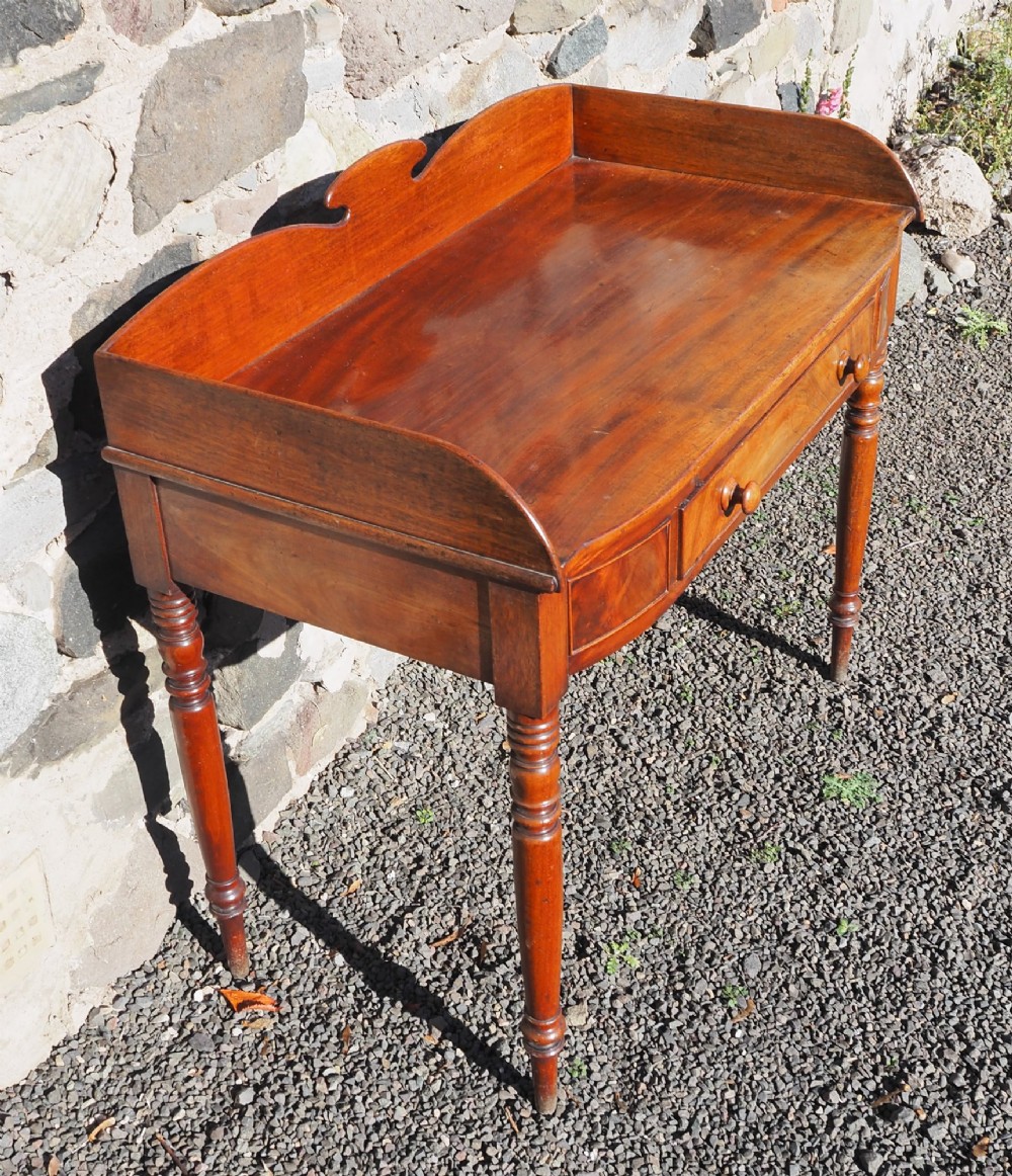 A Georgian mahogany dressing table featuring a raised gallery back, a single drawer with turned wooden knobs, and slender turned legs. View III