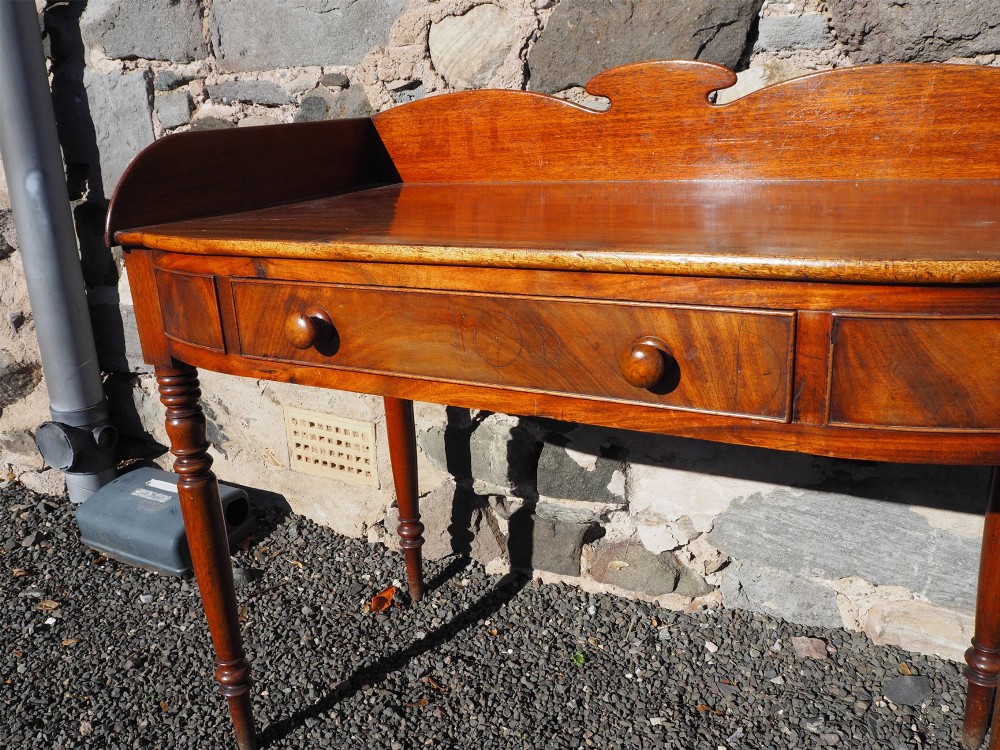 A Georgian mahogany dressing table featuring a raised gallery back, a single drawer with turned wooden knobs, and slender turned legs. View V