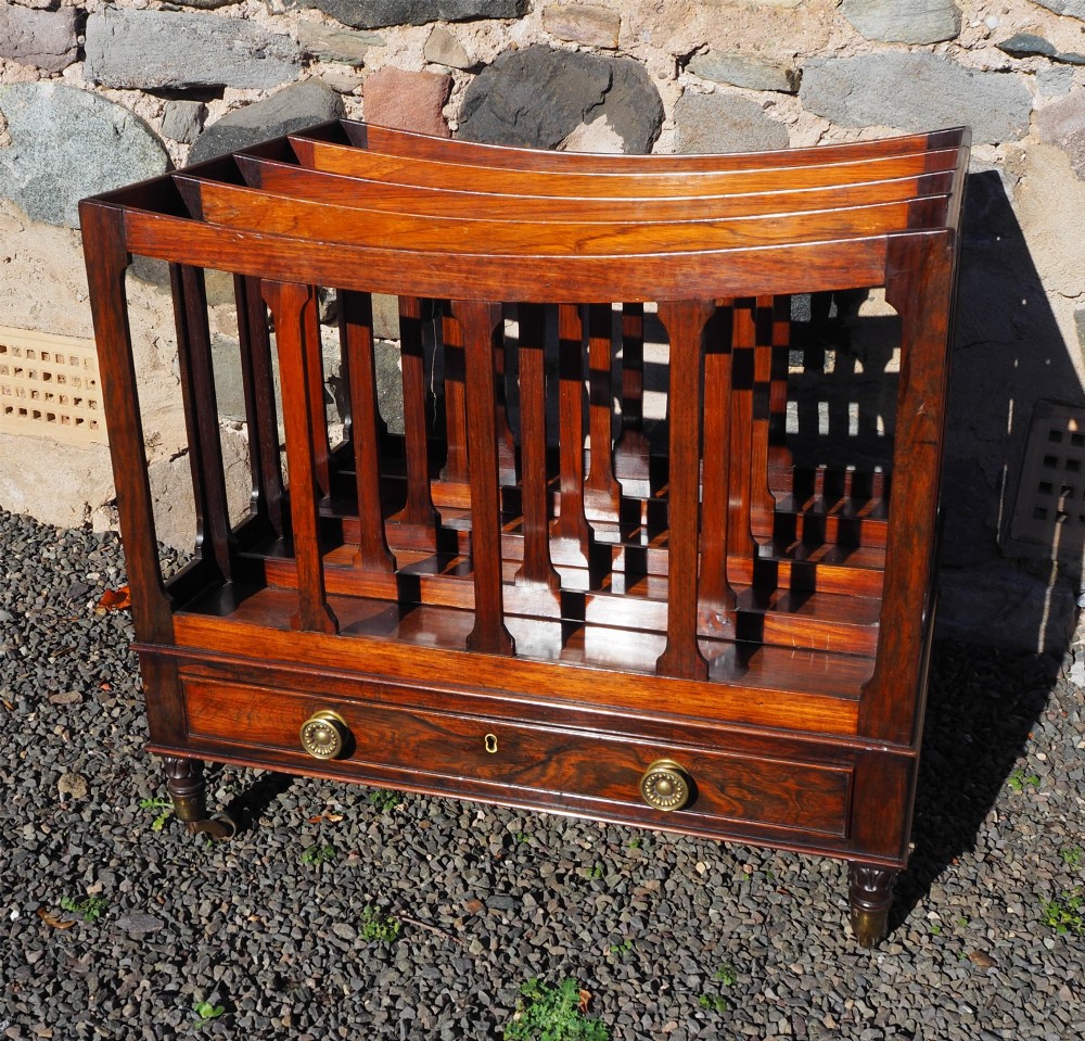 A 19th-century Regency rosewood canterbury with four slatted partitions, vertical supports, a single base drawer, brass knobs, and brass castors. View II