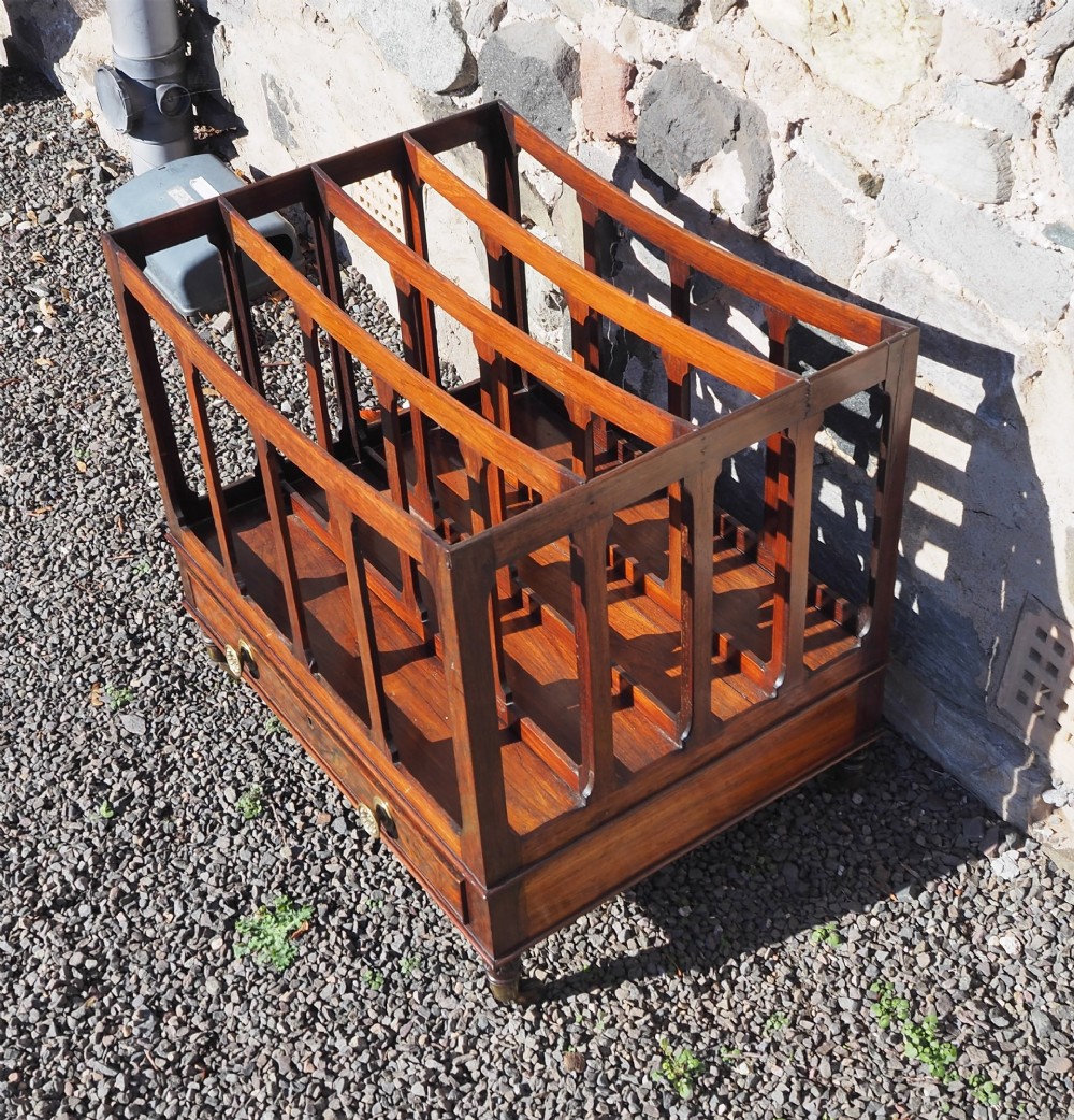 A 19th-century Regency rosewood canterbury with four slatted partitions, vertical supports, a single base drawer, brass knobs, and brass castors. View III
