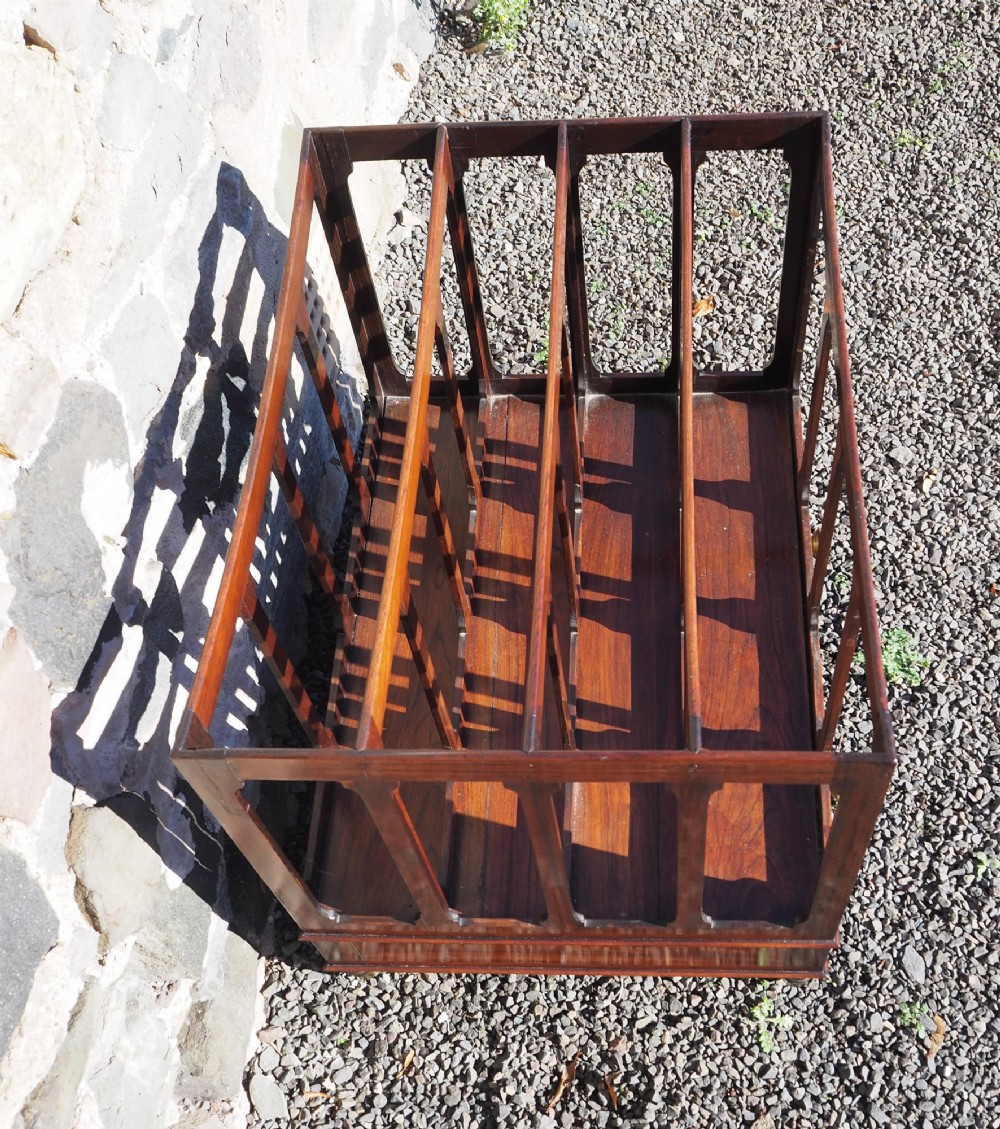 A 19th-century Regency rosewood canterbury with four slatted partitions, vertical supports, a single base drawer, brass knobs, and brass castors. View IV