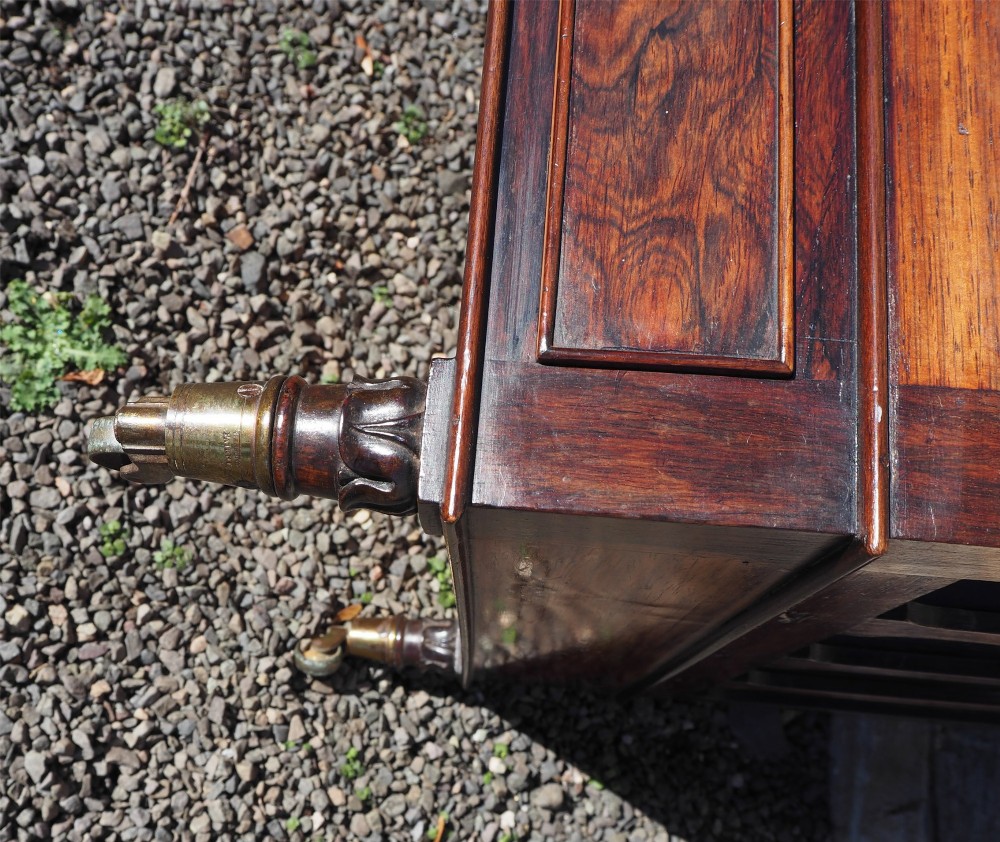 A 19th-century Regency rosewood canterbury with four slatted partitions, vertical supports, a single base drawer, brass knobs, and brass castors. View VII