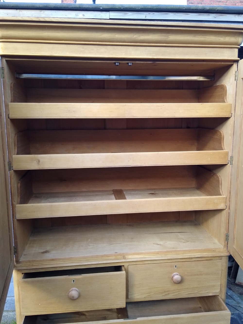 A Victorian rustic pine linen press featuring a moulded top cornice above two arched cupboard doors and a base with four drawers fitted with turned pine knobs. View VII