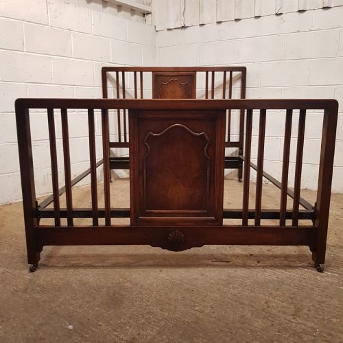 fig 1. An antique dark walnut double bedstead featuring a central arched panel flanked by vertical slats on both the headboard and footboard, set with metal side rails.