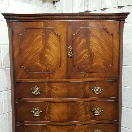 fig 2. A mahogany Chippendale style tallboy featuring upper cupboard doors with shaped moulding over four serpentine-front drawers with brass handles.
