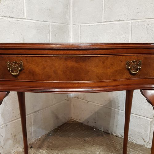 fig 1. A small burr walnut side table featuring a serpentine-fronted drawer with brass handles, resting on slender cabriole legs.