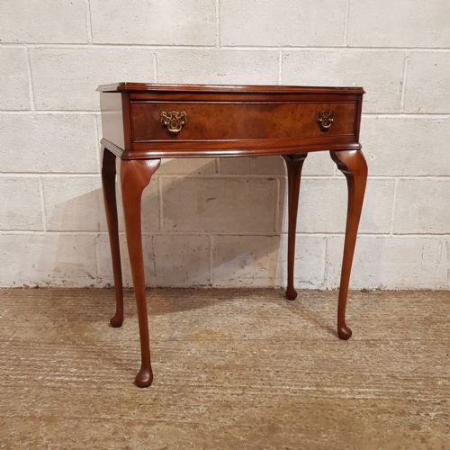 fig 2. A small burr walnut side table featuring a serpentine-fronted drawer with brass handles, resting on slender cabriole legs.
