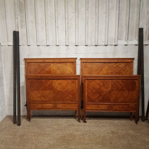 fig 1. A pair of late Victorian golden satinwood single bed frames featuring geometric veneer panels and molded crest rails on brass castors.