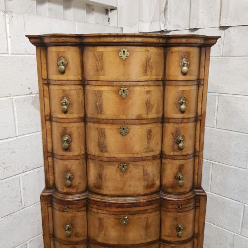fig 2. A tall Queen Anne style burr walnut chest on chest with a serpentine front, brass drop handles, and cabriole legs.