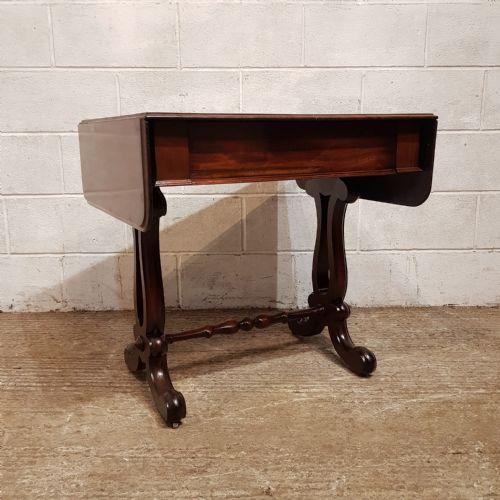 fig 1. A William IV mahogany sofa table featuring hinged drop-leaf side flaps, twin end supports, and a central turned stretcher.