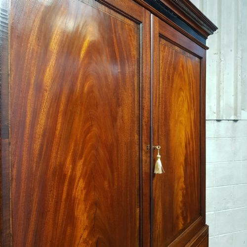 fig 2. A George III mahogany clothes press featuring flame mahogany panelled upper doors above a base with two short and two long drawers on bracket feet.