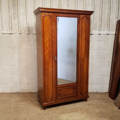 fig 1. A late Victorian mahogany single door wardrobe featuring a central mirrored panel flanked by chevron-veneered wood sections and topped with a moulded cornice.