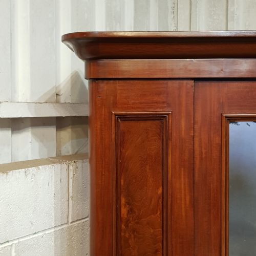 fig 1. A late Victorian single door mahogany wardrobe featuring a central mirrored door flanked by flame mahogany panels under a moulded cornice.
