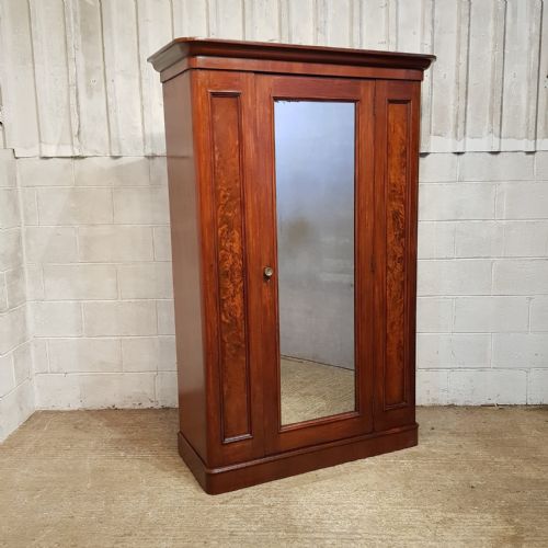 fig 2. A late Victorian single door mahogany wardrobe featuring a central mirrored door flanked by flame mahogany panels under a moulded cornice.